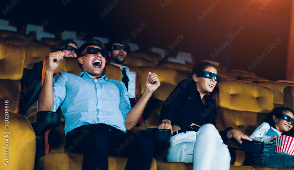 一群人在电影院里戴着3D眼镜看电影，饶有兴趣地看着屏幕，e