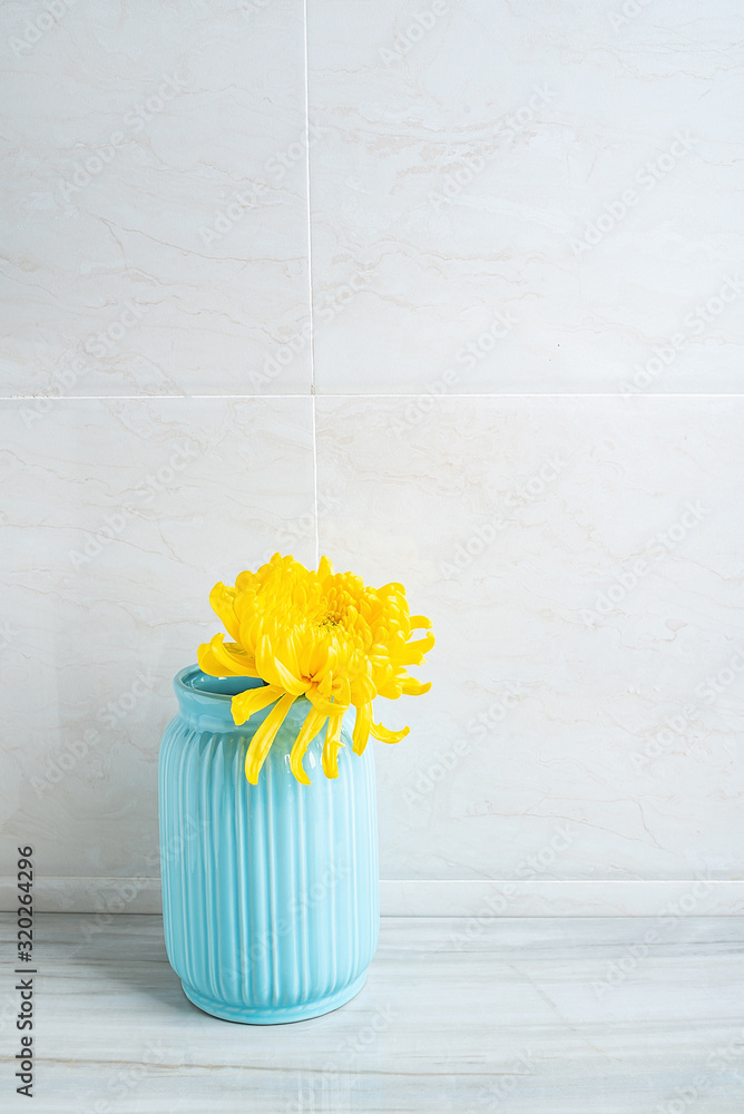 一瓶黄色菊花放在干净的浴室瓷砖台面上