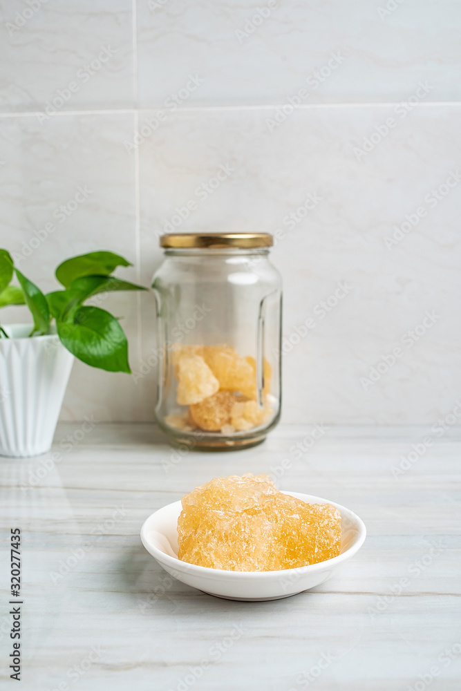 A dish of yellow rock sugar on the kitchen tile countertop