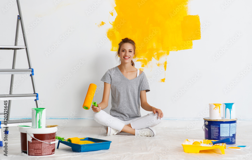 公寓里的维修。快乐的年轻女人粉刷墙壁。