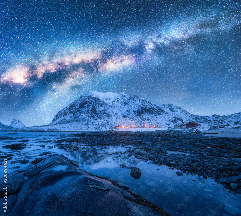冬季夜晚，银河系覆盖着白雪覆盖的山脉和岩石海滩。挪威罗弗敦群岛。C