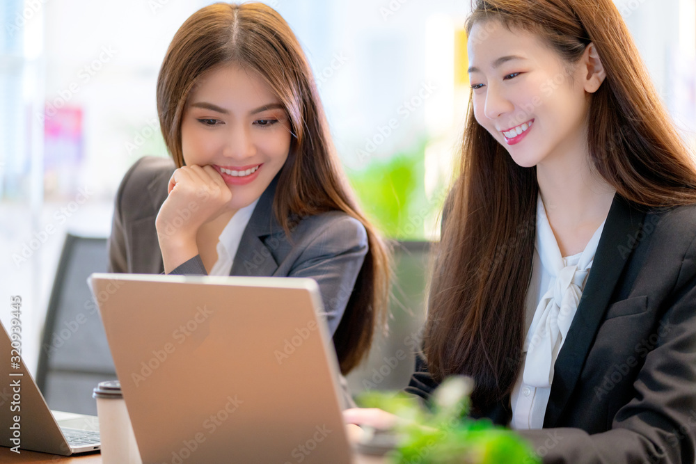 亚洲商业女性支持服务小组与笔记本电脑一起工作，带来幸福和快乐