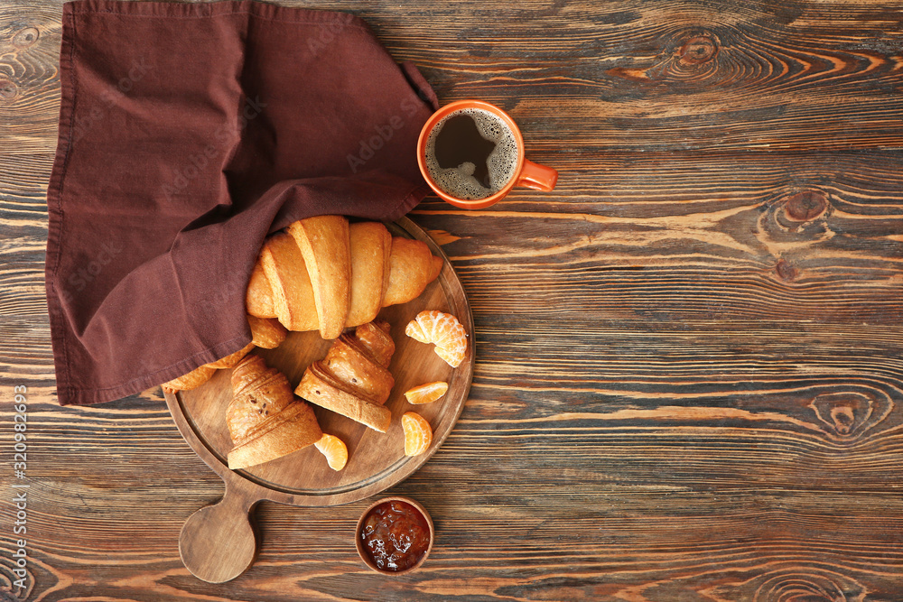 木板上放着美味的甜羊角面包、果酱和咖啡