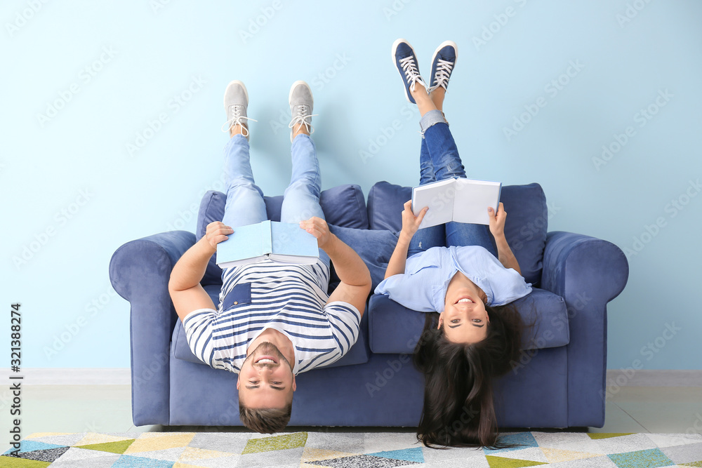 年轻夫妇躺在家里的沙发上看书