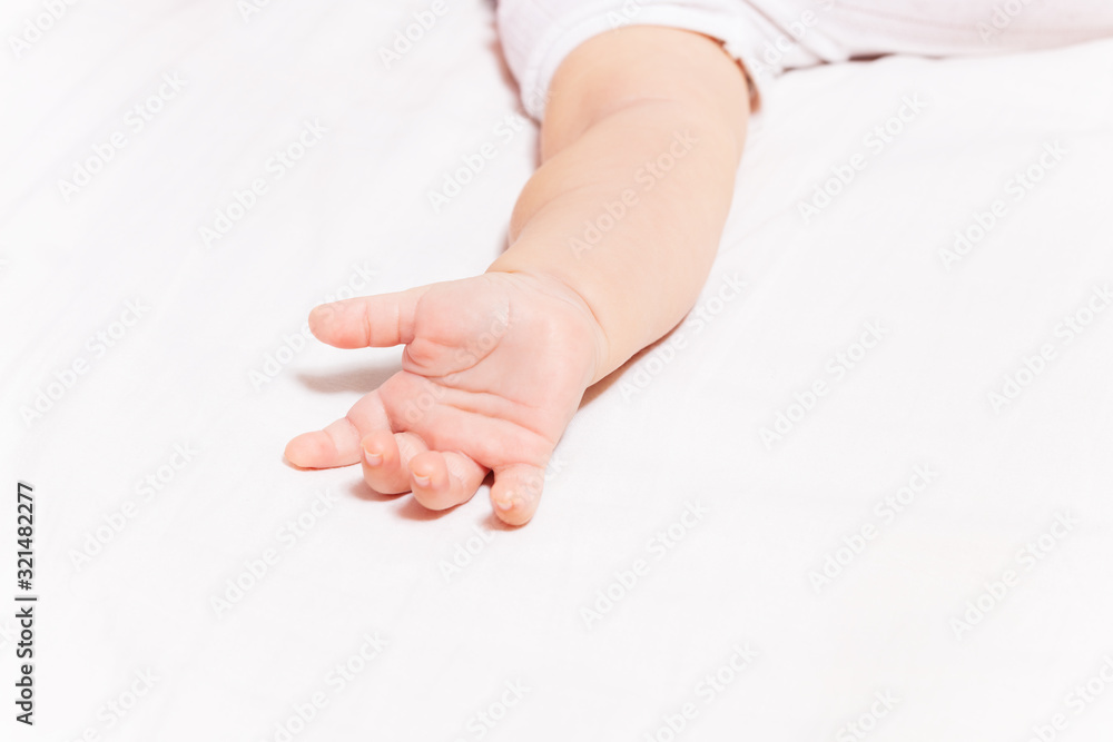 婴儿手躺在床单上的遮羞布照片