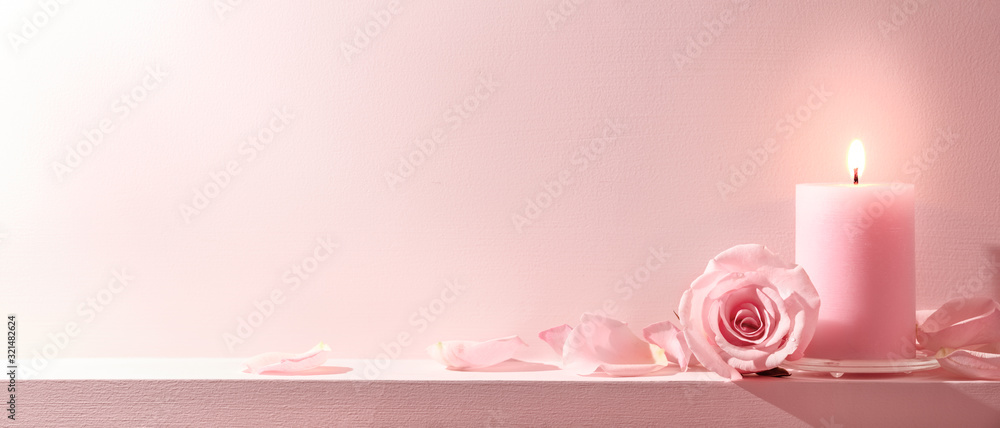 粉色背景上的粉色玫瑰和蜡烛