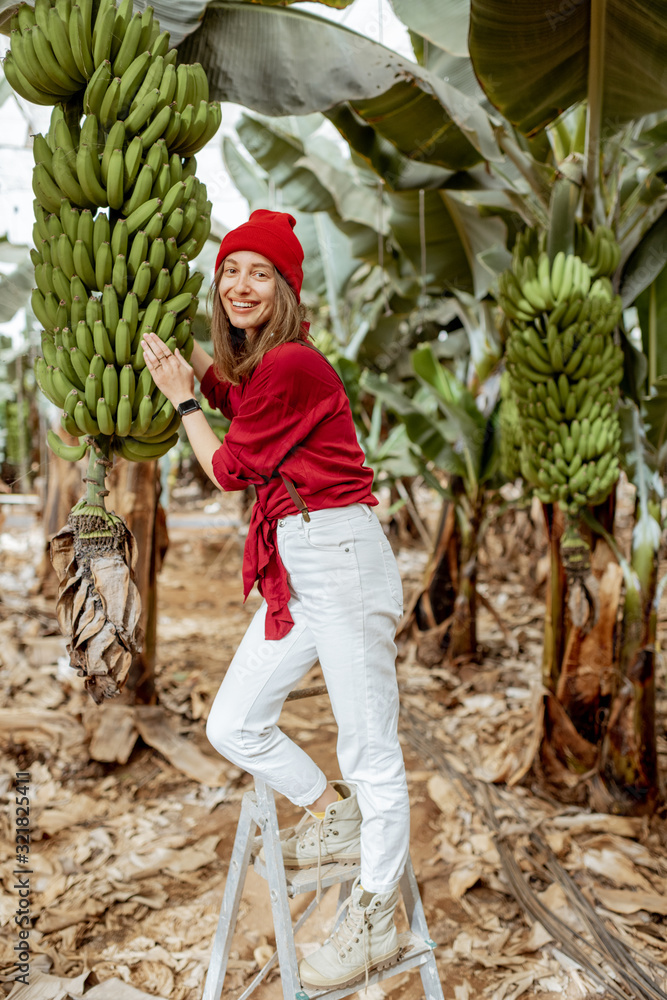 一个快乐的女人的画像，她是一个农民或游客，穿着红色衬衫，戴着帽子，站在芭蕉上