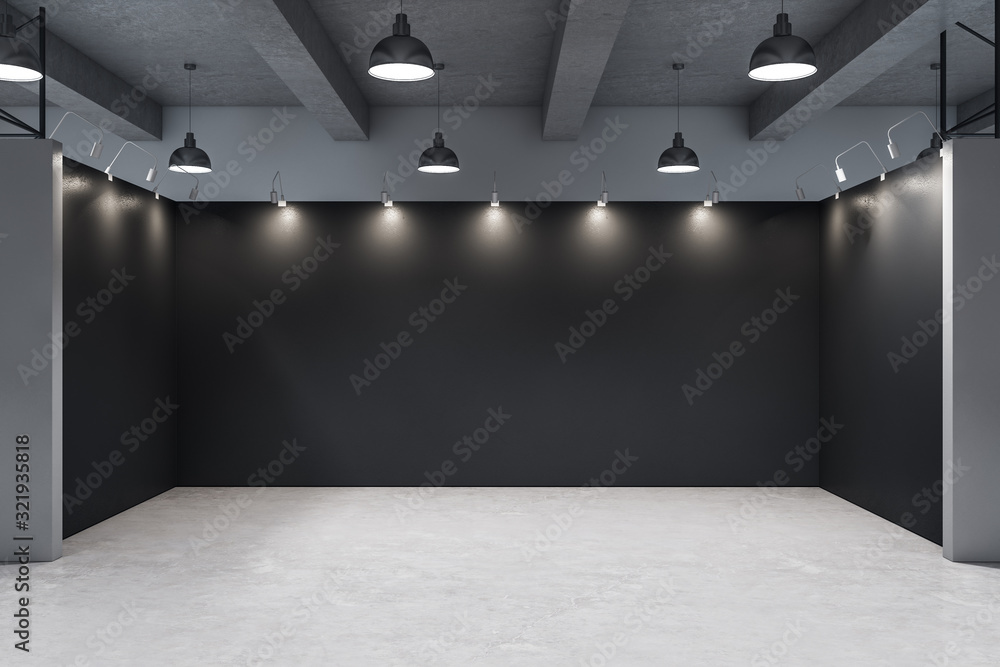 Gallery interior with empty black wall and concrete floor.