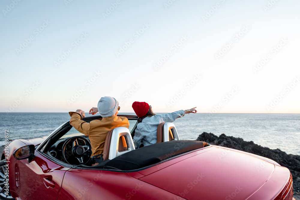 日落时分，一对情侣在海边乘坐敞篷车欣赏美丽的海景