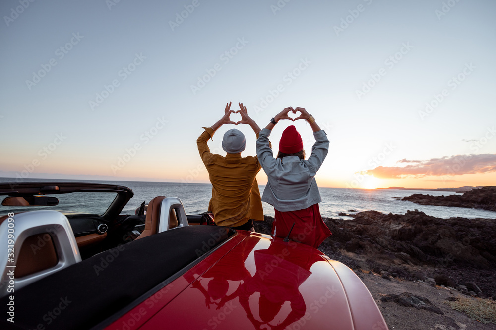 情侣们一起站在岩石海岸的汽车旁欣赏美丽的海景，sho