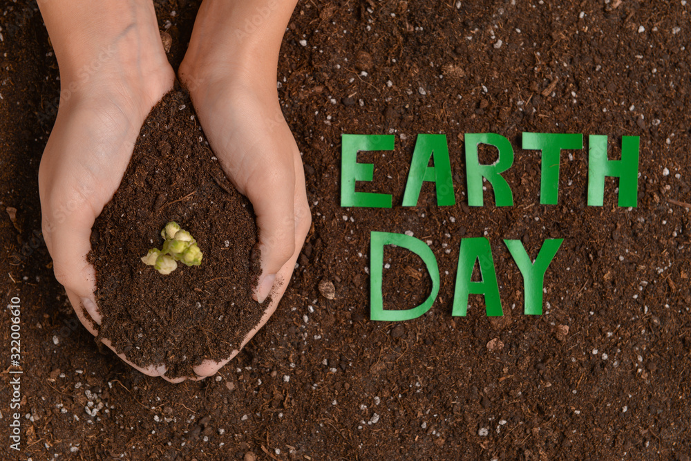 Female hands with soil and text EARTH DAY