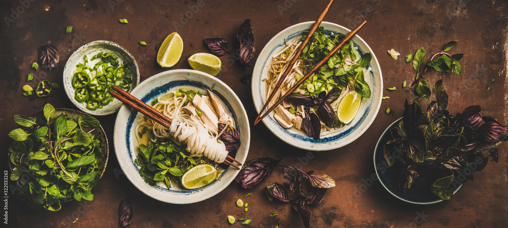 Asian cuisine lunch. Flat-lay of Vietnamese rice noodle chicken soup Pho Ga with fresh cilantro, soy