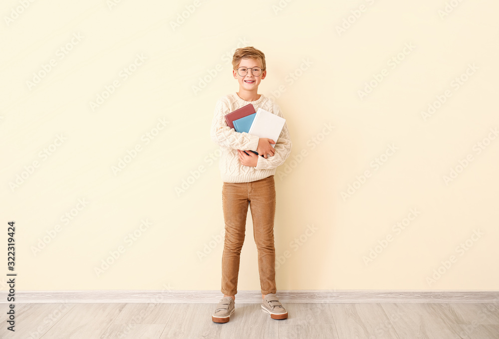 小男孩在彩色墙上拿着书