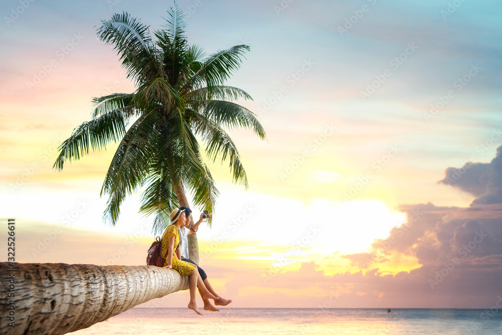 亚洲情侣坐在椰子树上