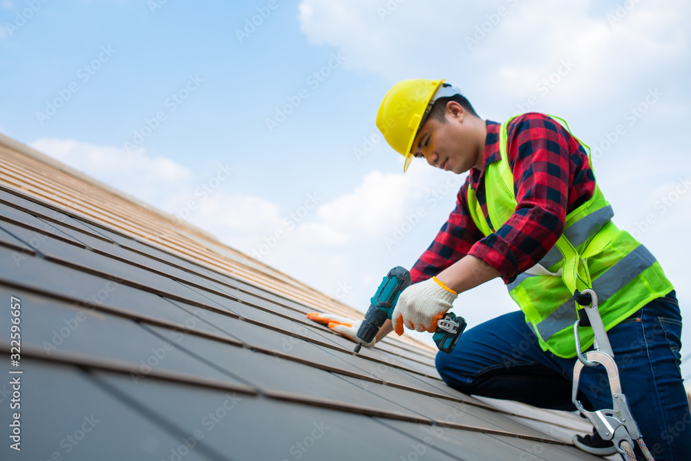 建筑工人用屋顶工具固定屋顶瓷砖，在屋顶上安全使用电钻