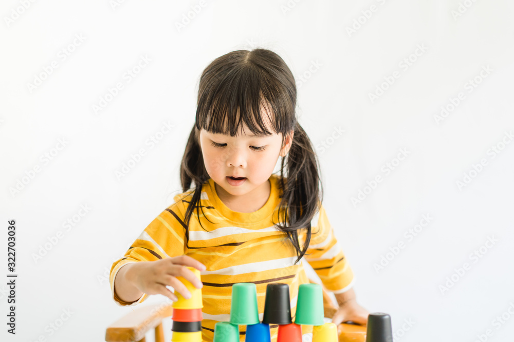 Little asian toddler girl playing stacking cups learning materials in a montessori methodology schoo