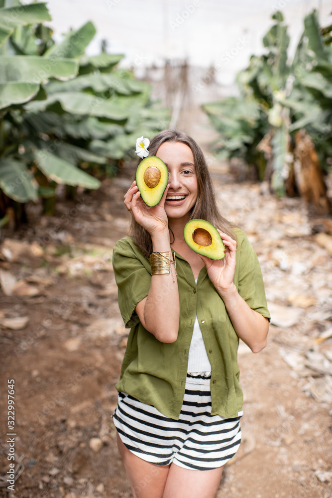 一个年轻微笑的女人在户外用切好的鳄梨掩面的肖像。蔬菜的概念