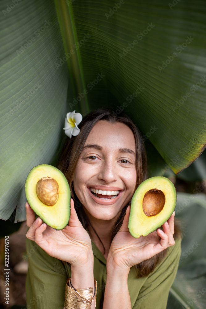 一个年轻可爱的女人的肖像，她在户外的香蕉叶中切着鳄梨浆果。概念