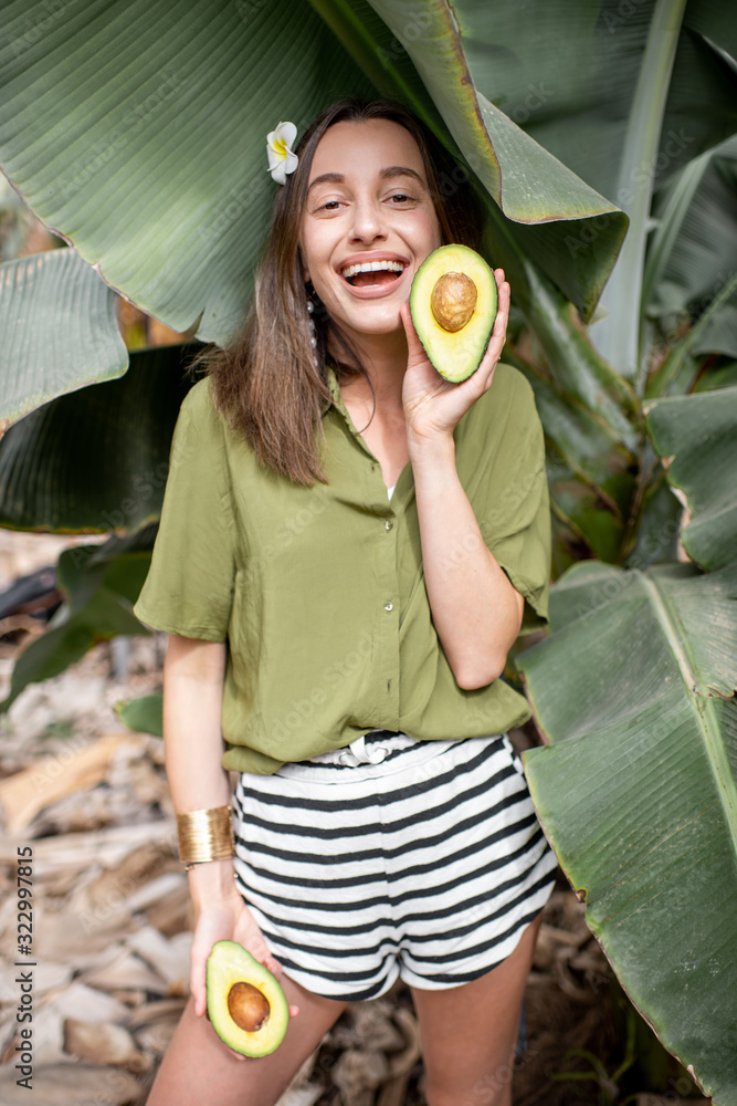 一位年轻可爱的女士的肖像，她在户外的香蕉叶中切着鳄梨浆果。概念