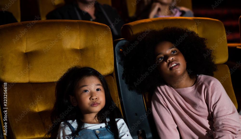 两个非洲和亚洲的孩子在电影院玩得很开心，喜欢看电影