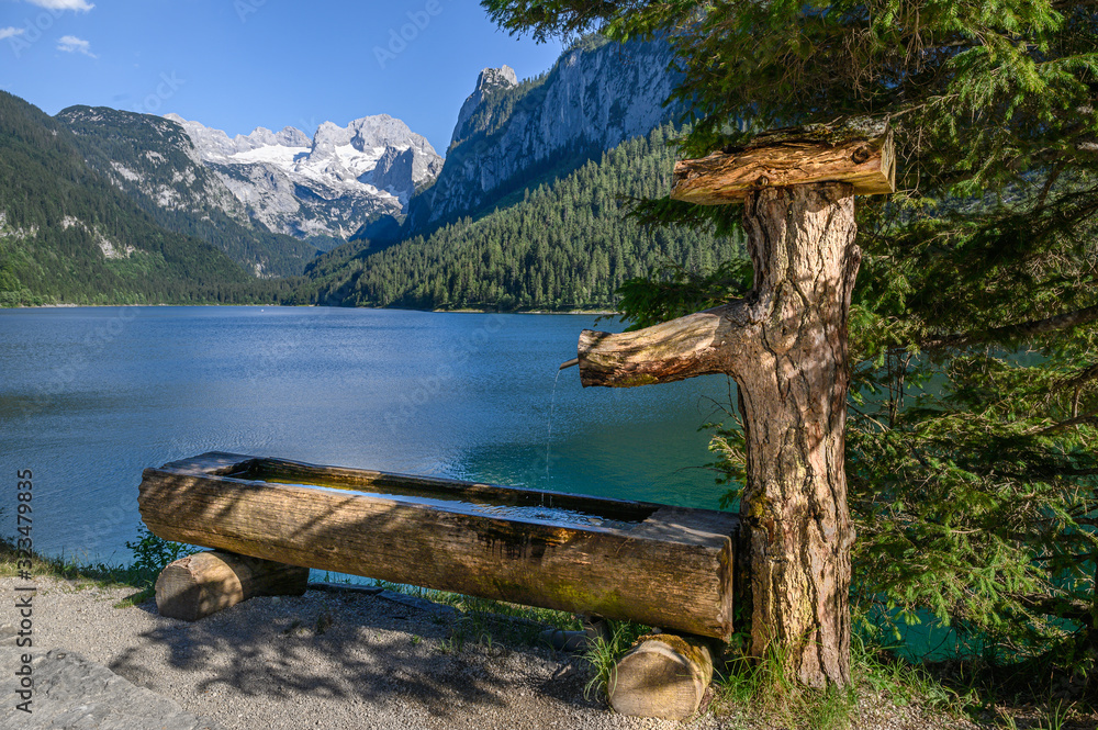 Fountain in front of the idyllic Gosausee with glaciated mountains in the background, Austria