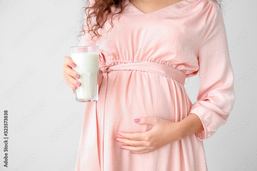 怀孕的非裔美国妇女，灰色背景下有牛奶