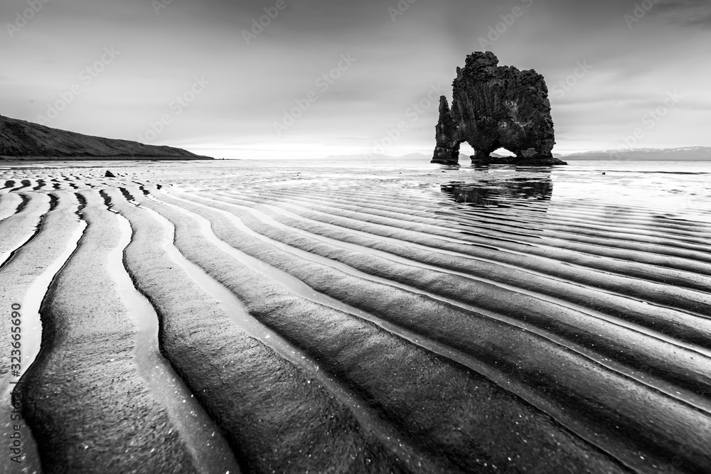 Drammatic landscape with famous Hvitserkur rock and dark wavy sand after the tide. Vatnsnes peninsul