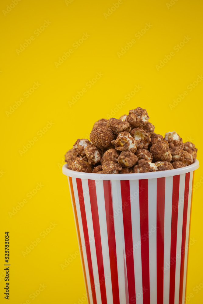 红色爆米花杯里的黄油爆米花，黄色背景的房子或电影院里的零食