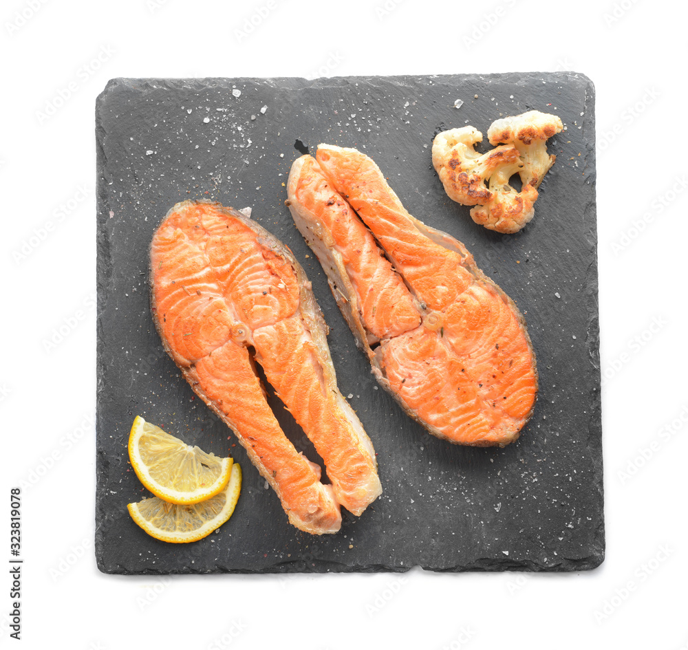 Slate plate with fried salmon on white background
