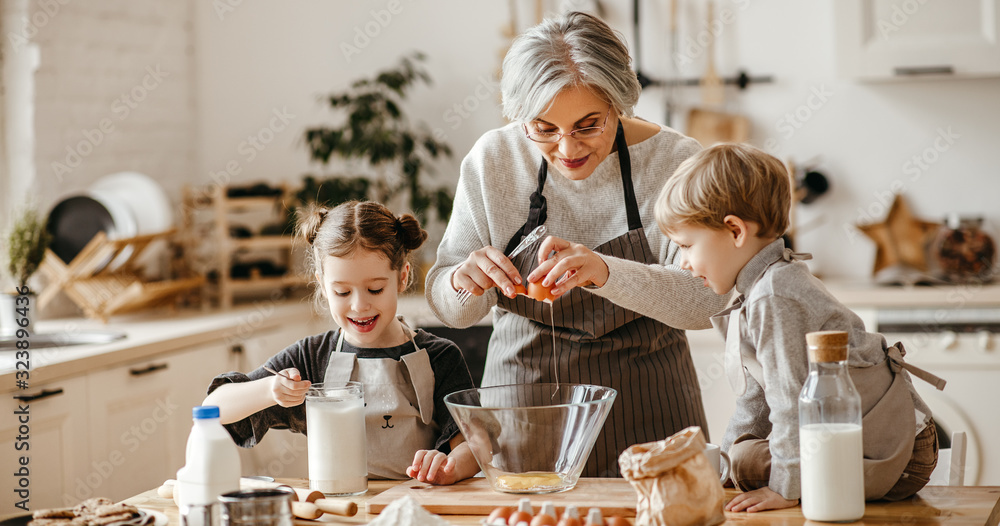幸福家庭的祖母和孙子在厨房做饭，揉面团，烤饼干。