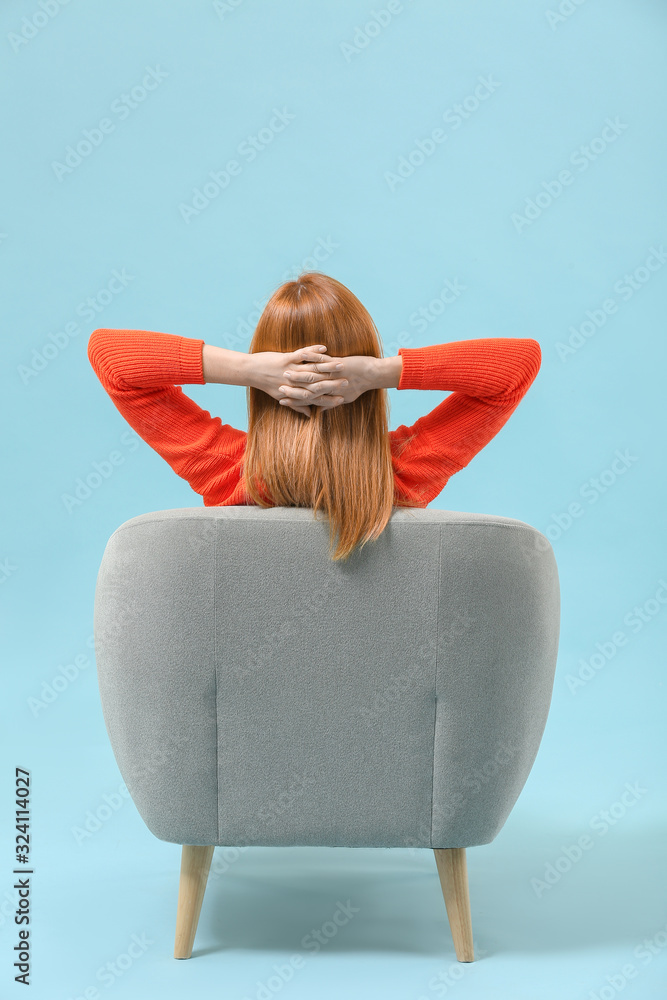 美丽的女人在扶手椅上放松，背景是彩色的，后视