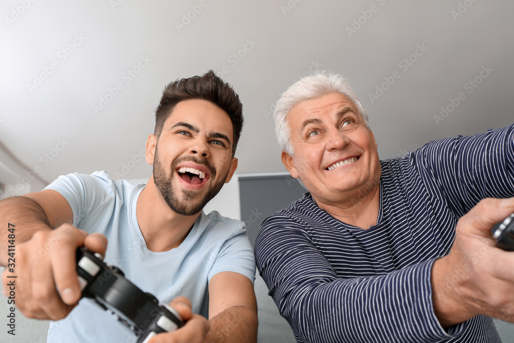 年轻人和他的父亲在家玩电子游戏