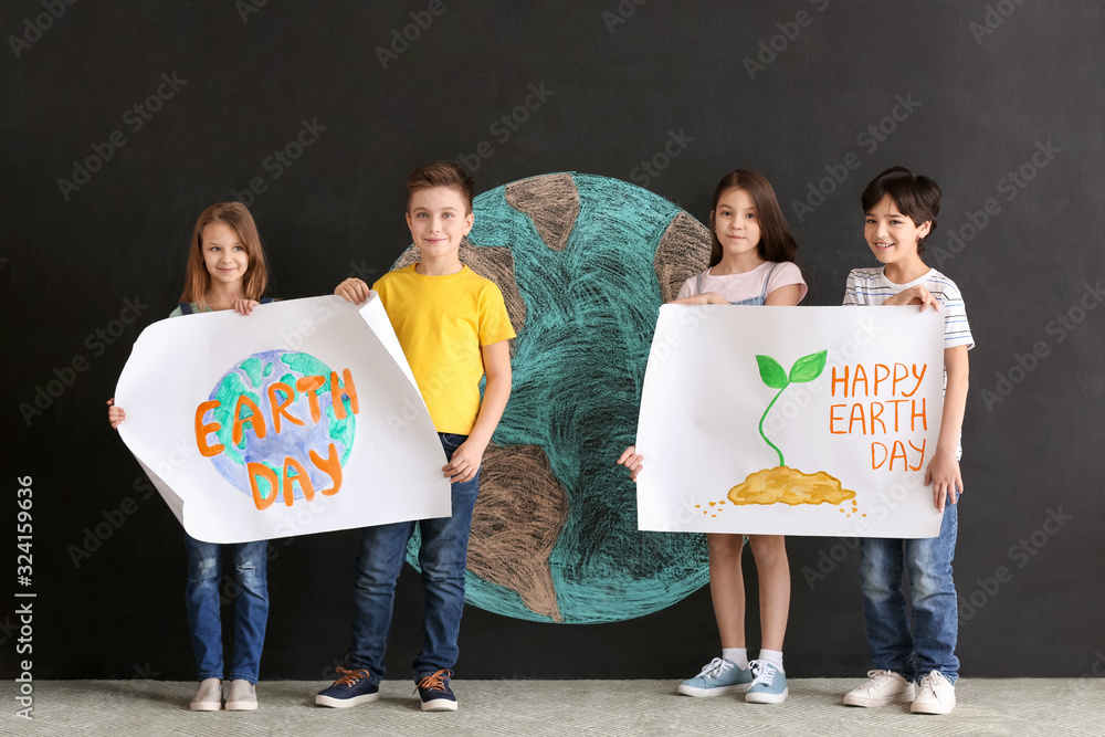 Little children with posters and drawing of planet on dark background. Earth Day celebration
