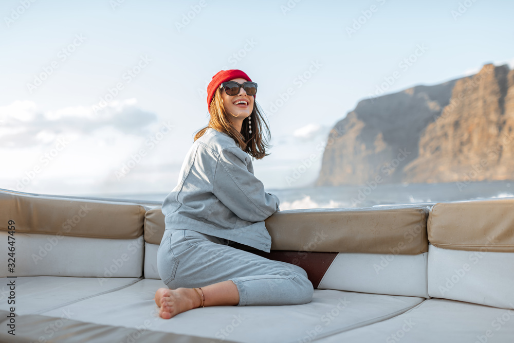一位年轻女旅行者的肖像，她戴着红帽子，穿着牛仔裤，在附近的游艇上航行