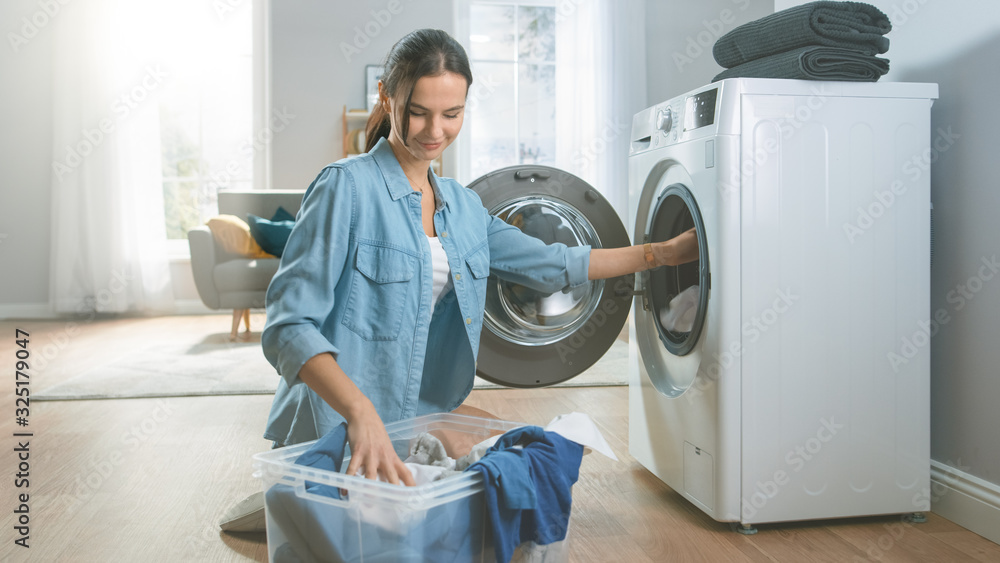 Beautiful and Happy Brunette Young Woman Comes Towards the Washing Machine in Homely Jeans Clothes. 