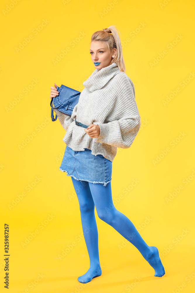 年轻女性，化着富有创意的妆，穿着彩色背景的保暖毛衣
