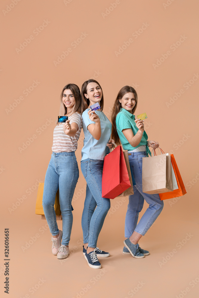 彩色背景下拿着信用卡和购物袋的年轻女性