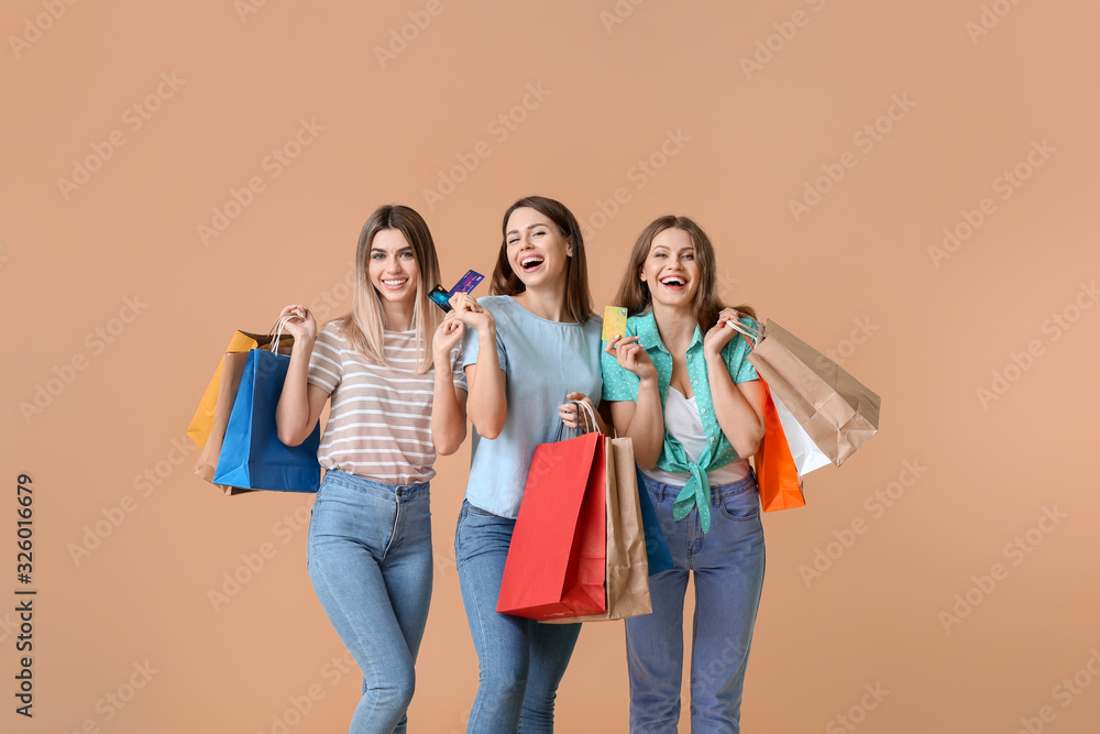 彩色背景下拿着信用卡和购物袋的年轻女性