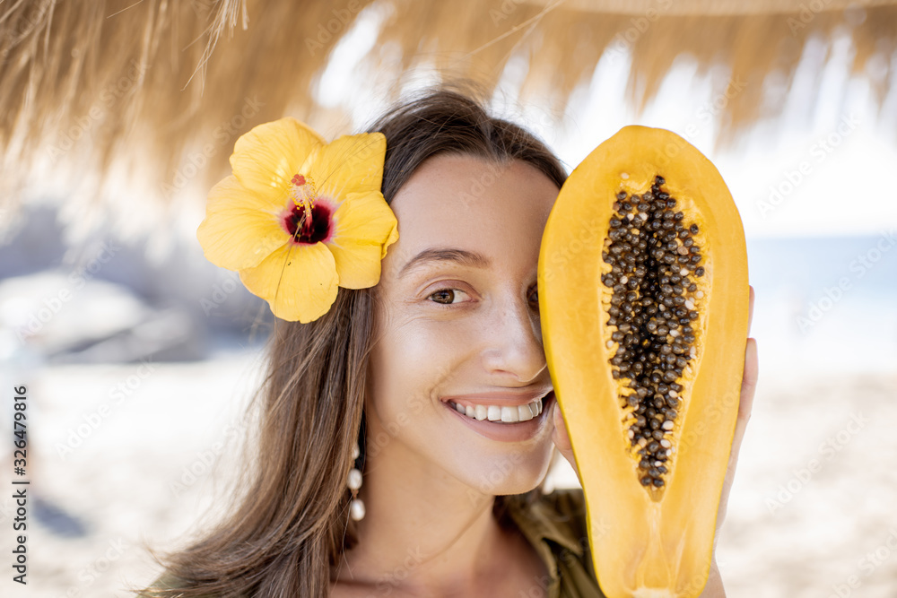 阳光下的海滩度假胜地，一个可爱的夏日女孩的面部肖像，带着木瓜果和头发花