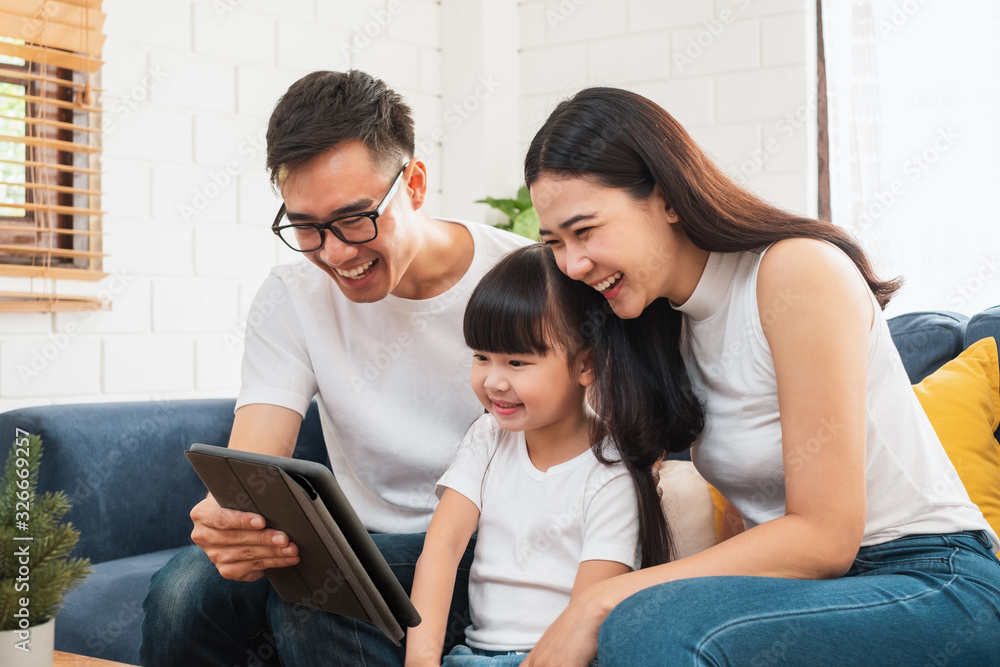 快乐的亚洲家庭在沙发/家里一起玩游戏、平板电脑教育