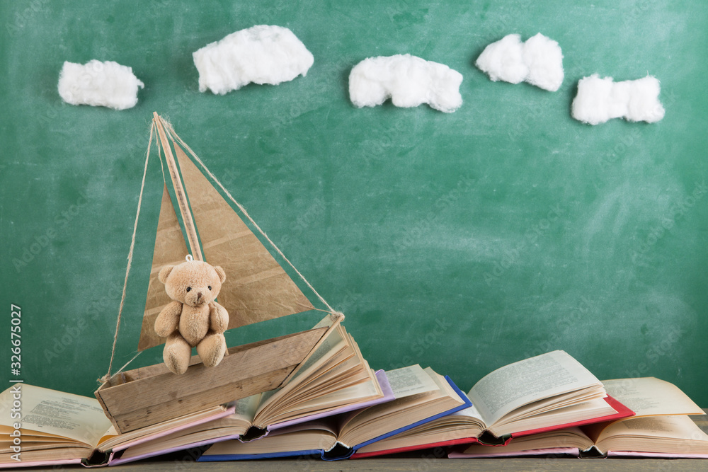 Education is a journey concept, toy boat and books like a sea waves on the chalkboard background, in
