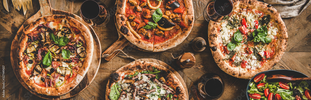 披萨派对晚餐。各种意大利披萨、沙拉和红酒放在玻璃杯里，放在r上。