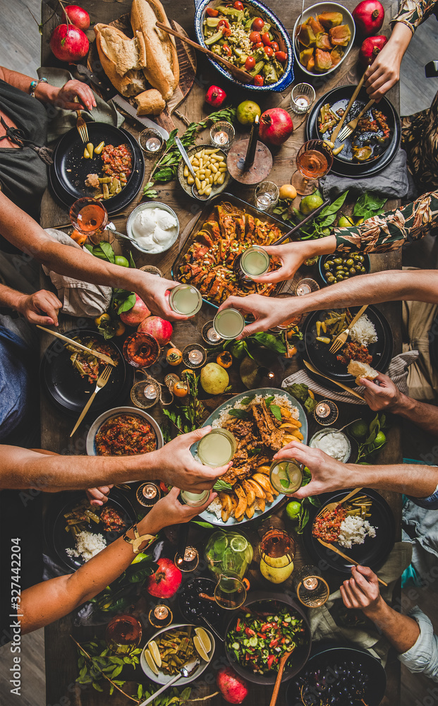 一家人在乡村餐桌上碰杯，享用土耳其美食羊排、木瓜、绿色