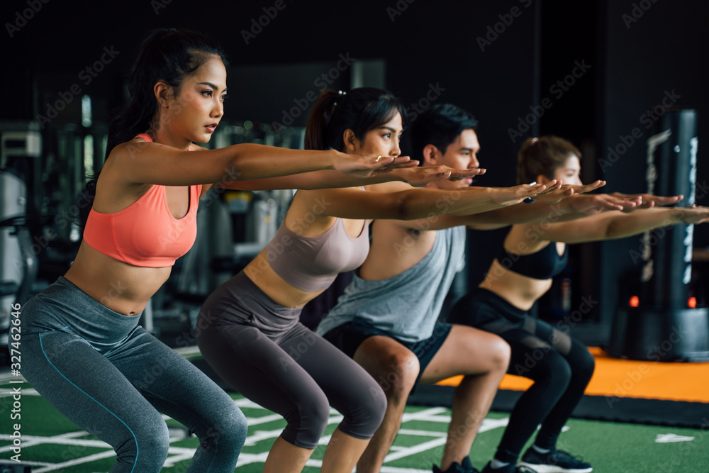 一群穿着运动服的运动型亚洲年轻人在健身房做深蹲和锻炼的特写