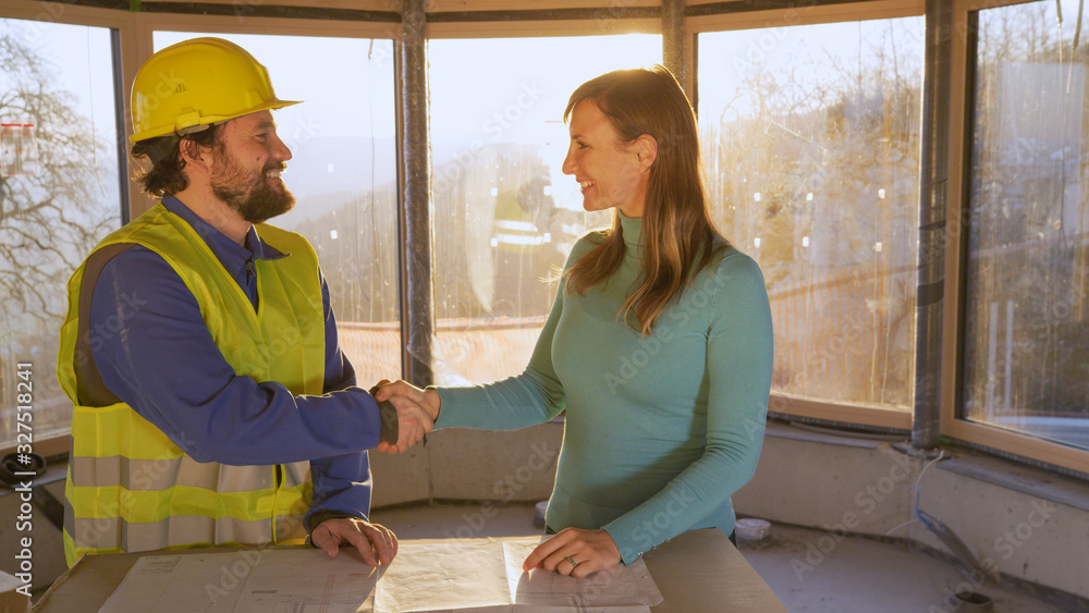 CLOSE UP: Happy young woman and contractor shake hands on a sunny morning.