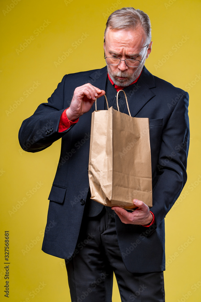 大胡子成熟男人，黄色背景纸袋。打折。网上购物。