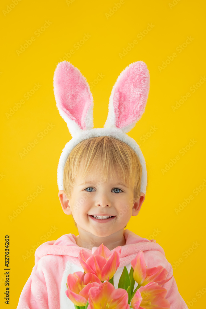 Funny kid wearing Easter bunny against yellow background