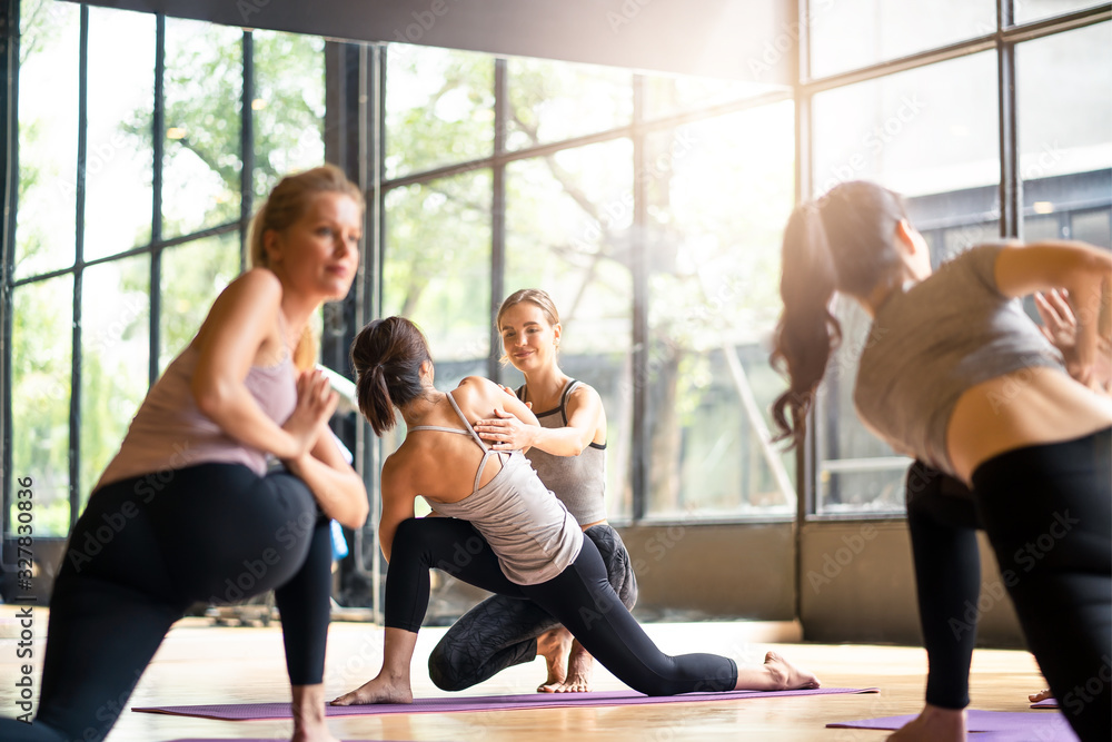 一群多种族的人在健身俱乐部学习瑜伽课。女性高加索教练女性