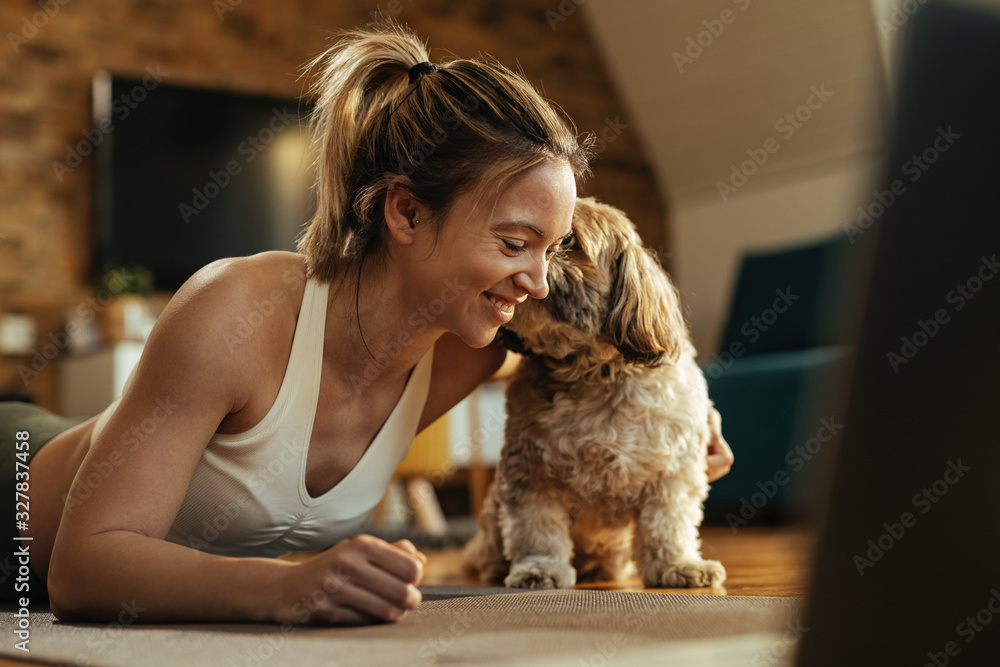 快乐的运动女性在家锻炼时与她的狗一起享受。