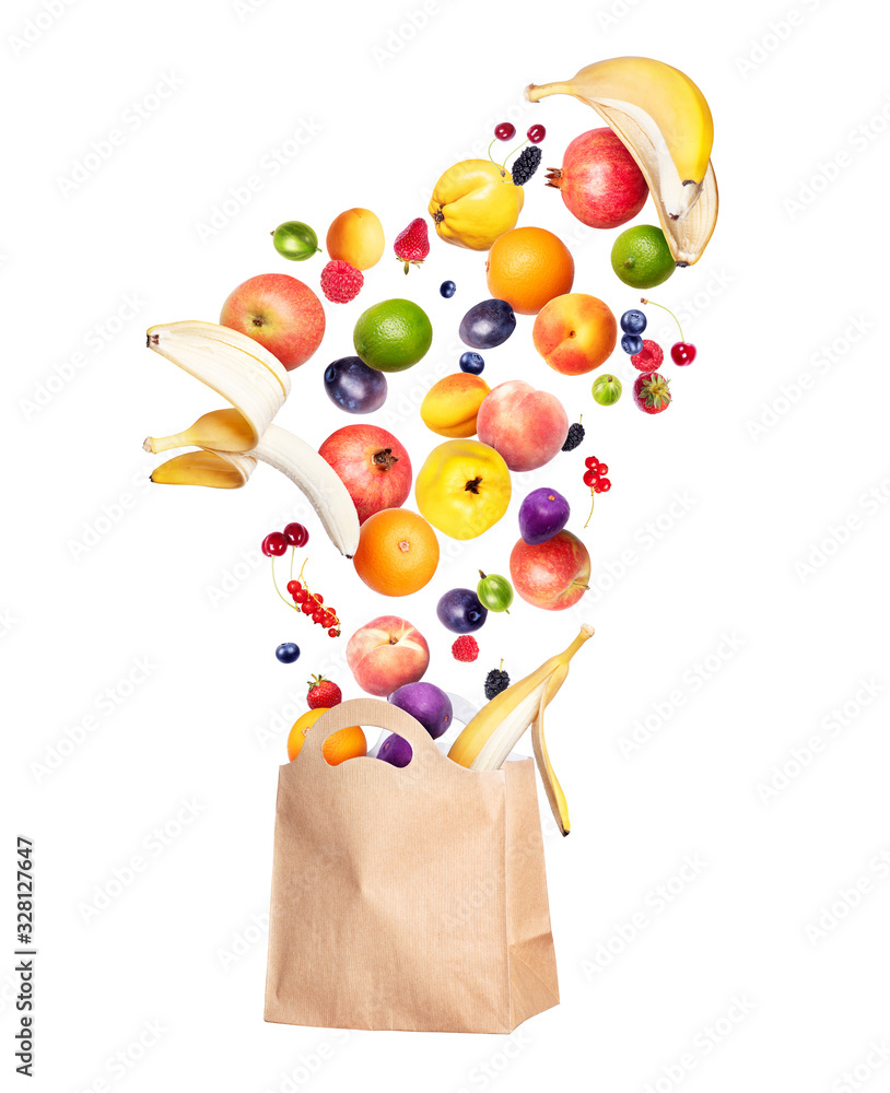 各种水果和浆果从一个杂货纸袋里飞出来，孤立在白色背景上
